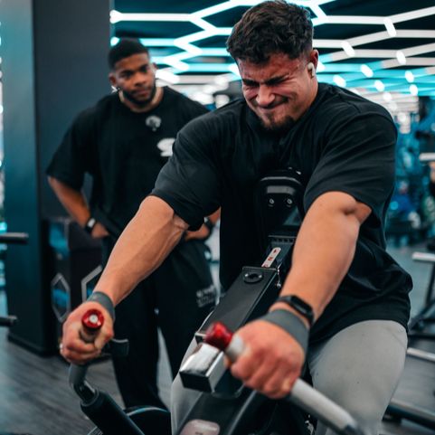 Coachen kör hårt på en airbike i gymmet.